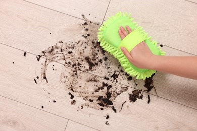 Photo of Woman cleaning dirt on wooden floor, closeup