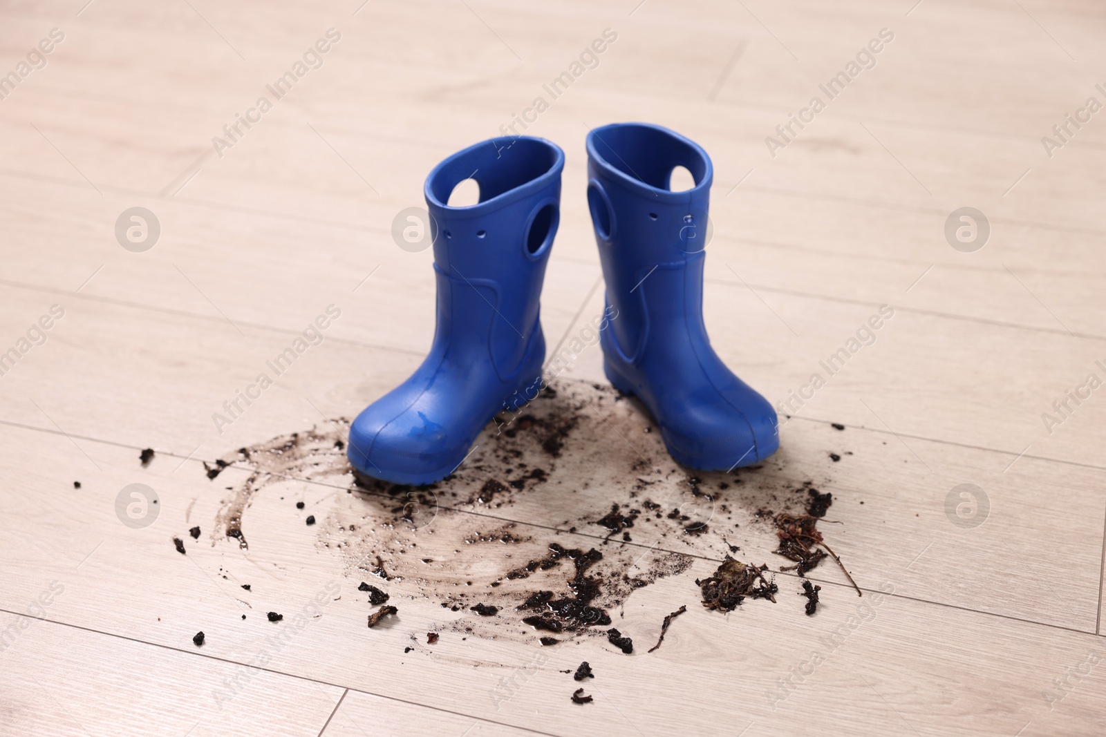 Photo of Rubber boots with mud on wooden floor