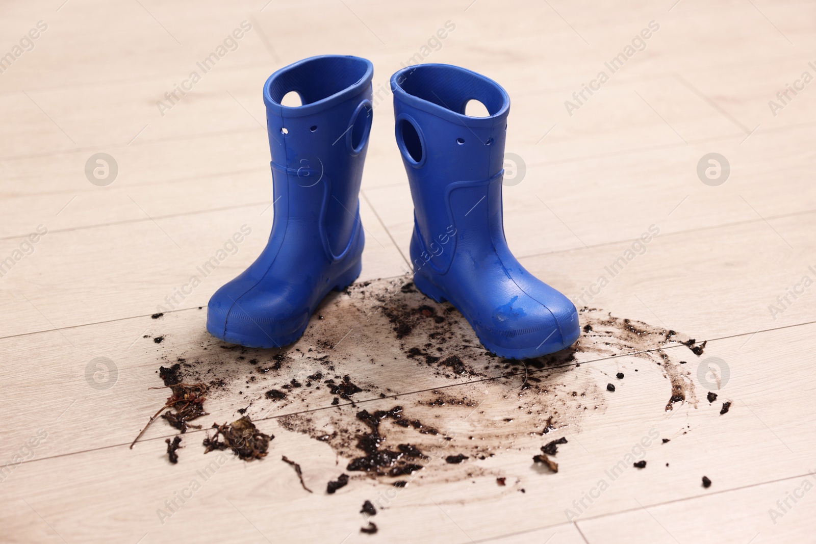 Photo of Rubber boots with mud on wooden floor