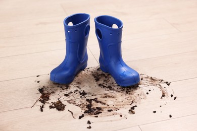 Photo of Rubber boots with mud on wooden floor