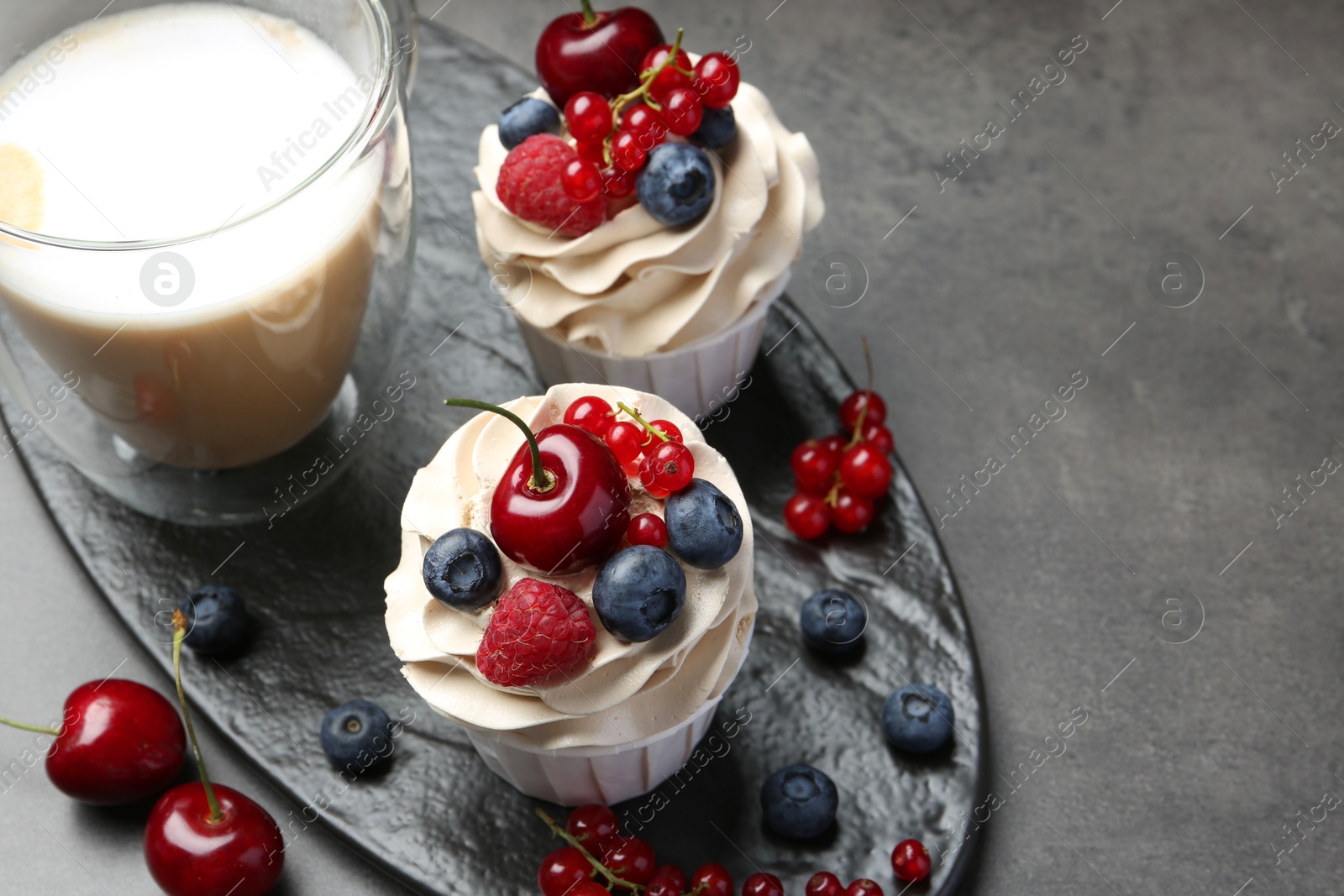 Photo of Tasty cupcakes with different berries on grey table, above view. Space for text