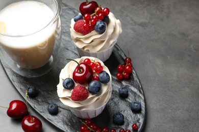 Photo of Tasty cupcakes with different berries on grey table, above view. Space for text