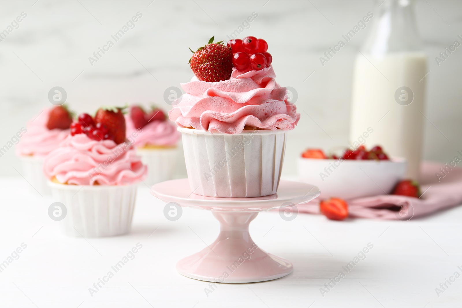 Photo of Tasty cupcakes with strawberries and red currants on white table