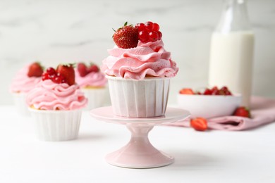 Photo of Tasty cupcakes with strawberries and red currants on white table