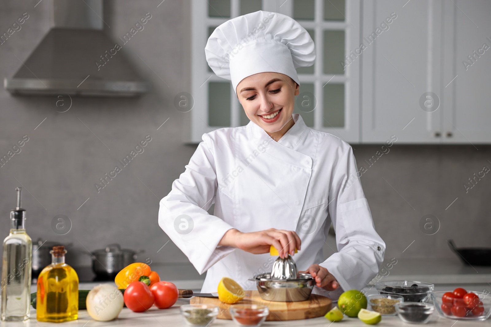 Photo of Woman squeezing juice out of lemon at table in kitchen