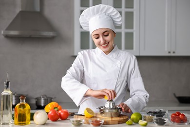 Woman squeezing juice out of lemon at table in kitchen