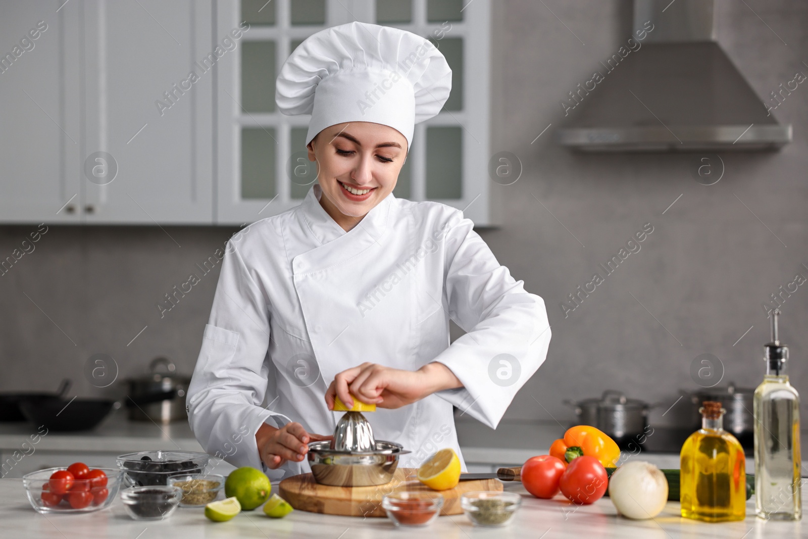 Photo of Woman squeezing juice out of lemon at table in kitchen