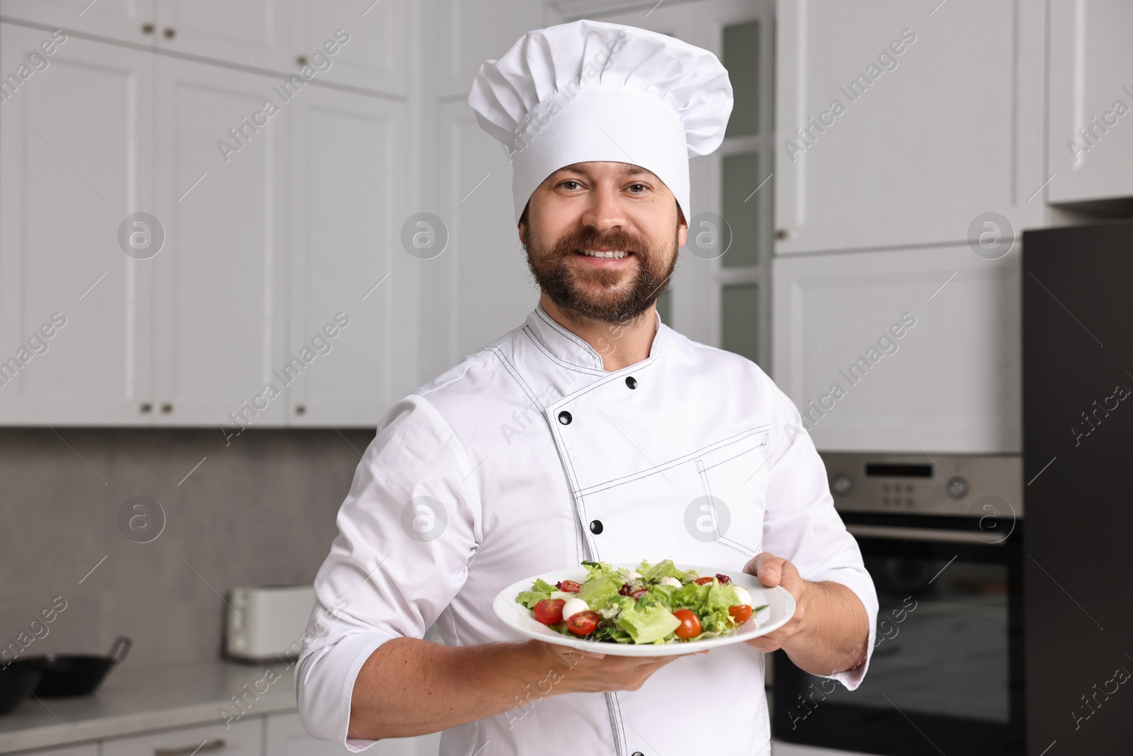 Photo of Professional chef with delicious salad in kitchen