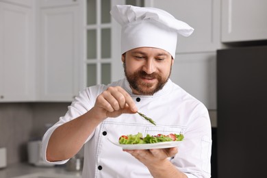 Photo of Professional chef decorating delicious dish with rosemary in kitchen