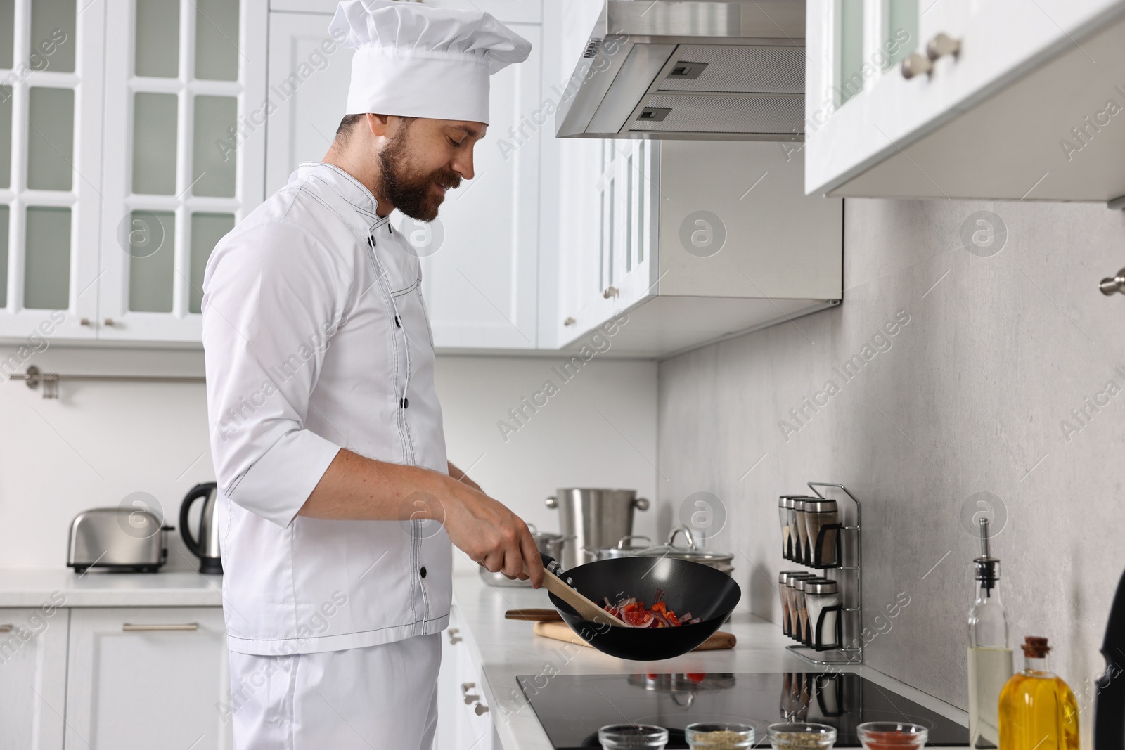 Photo of Professional chef cooking delicious food in frying pan indoors