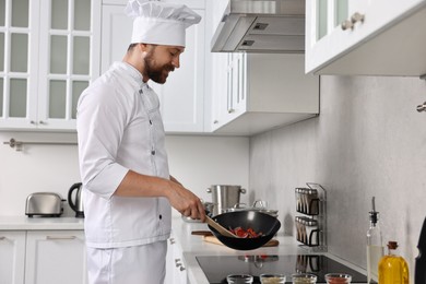 Professional chef cooking delicious food in frying pan indoors