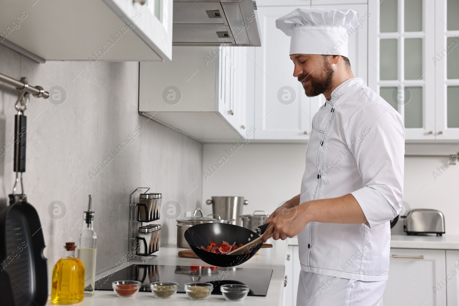 Photo of Professional chef cooking delicious food in frying pan indoors