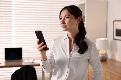 Portrait of beautiful businesswoman with smartphone in office