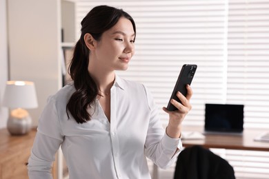 Photo of Portrait of beautiful businesswoman with smartphone in office