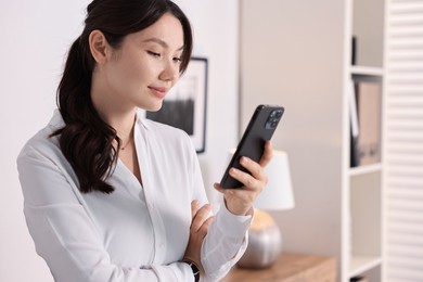 Photo of Portrait of beautiful businesswoman with smartphone in office