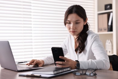 Beautiful young businesswoman using smartphone in office