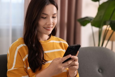 Portrait of smiling woman with smartphone at home