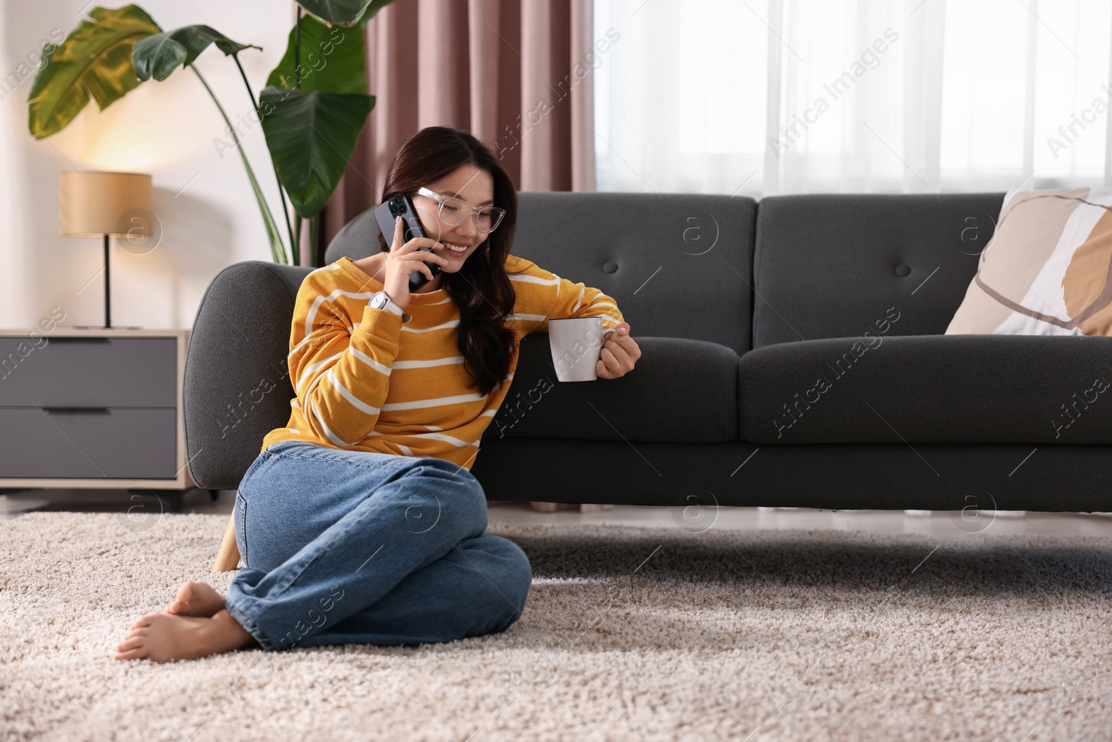 Photo of Smiling woman talking on smartphone at home