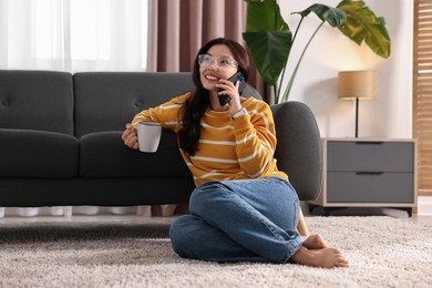 Photo of Smiling woman talking on smartphone at home