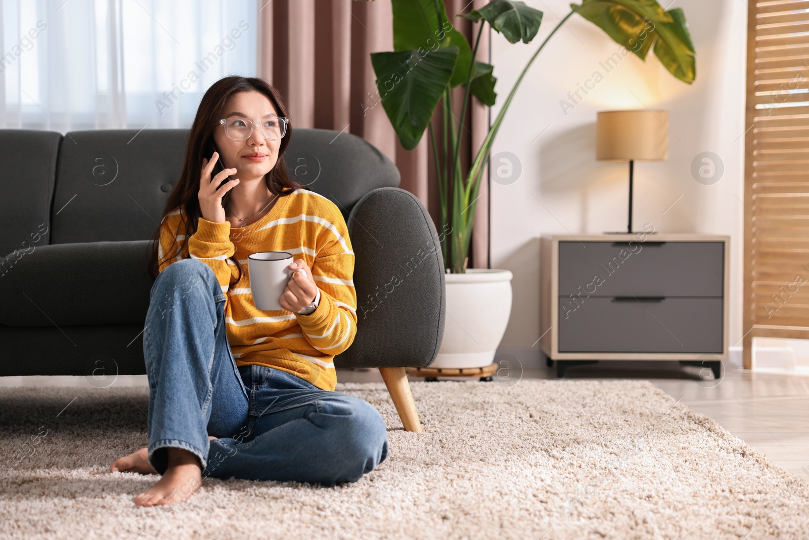 Photo of Beautiful woman talking on smartphone at home