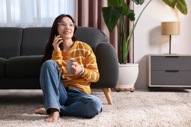 Photo of Smiling woman talking on smartphone at home