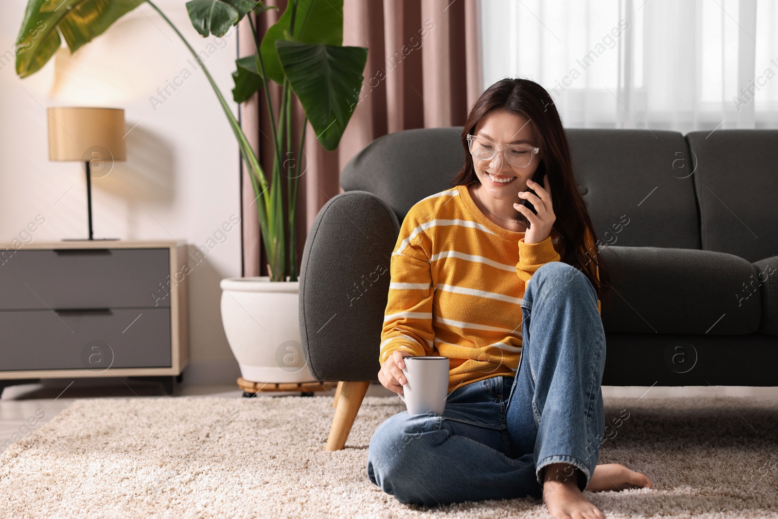 Photo of Smiling woman talking on smartphone at home