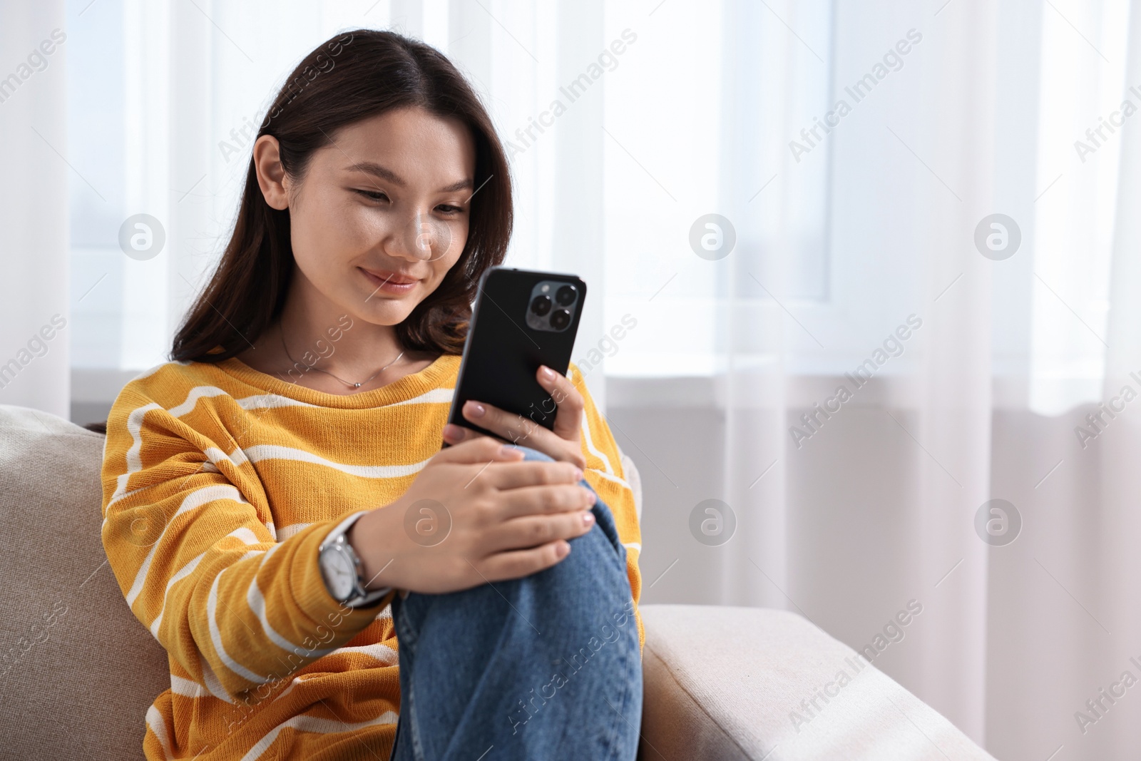 Photo of Beautiful woman using smartphone at home. Space for text