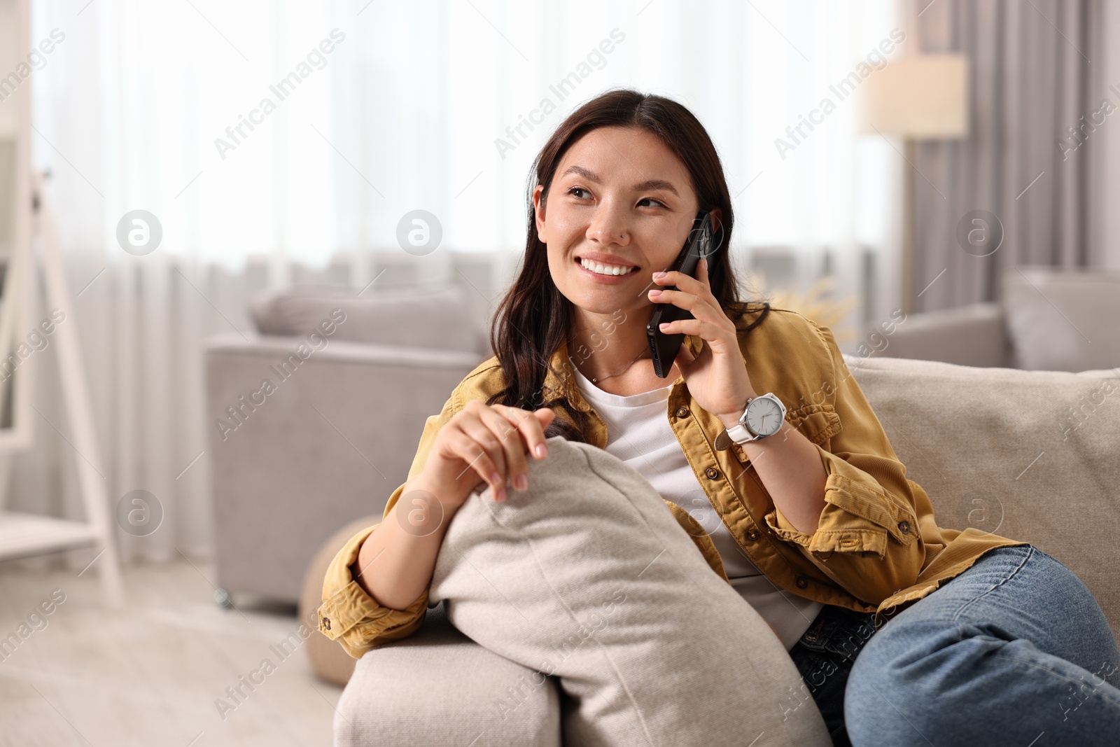 Photo of Smiling woman talking on smartphone at home. Space for text