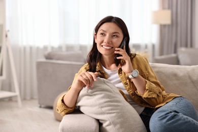 Smiling woman talking on smartphone at home. Space for text