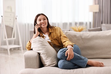 Smiling woman talking on smartphone at home