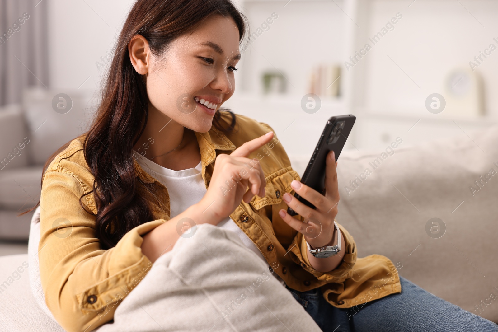 Photo of Portrait of smiling woman with smartphone at home