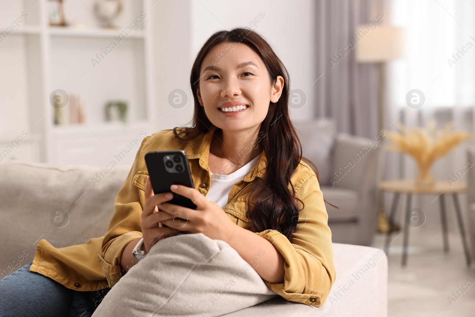 Photo of Portrait of smiling woman with smartphone at home