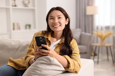 Portrait of smiling woman with smartphone at home