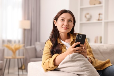 Photo of Beautiful woman with smartphone at home. Space for text