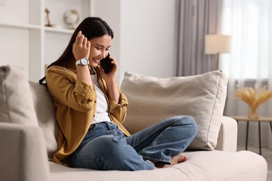 Photo of Smiling woman talking on smartphone at home