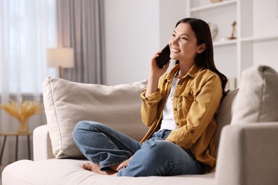 Photo of Smiling woman talking on smartphone at home