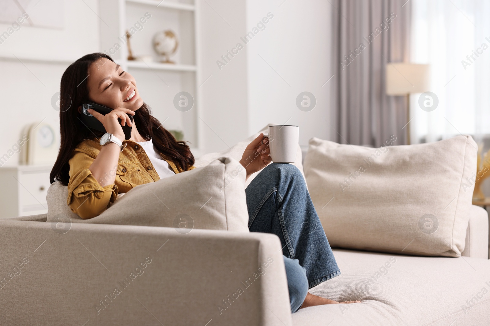 Photo of Smiling woman talking on smartphone at home