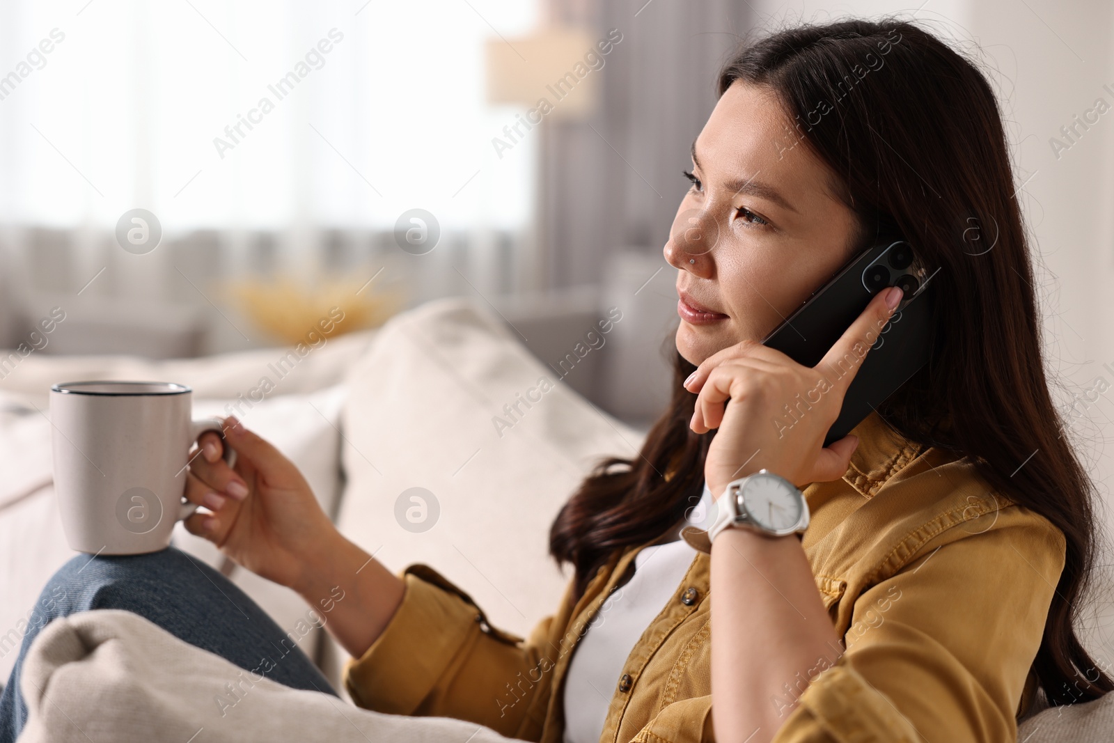 Photo of Beautiful woman talking on smartphone at home