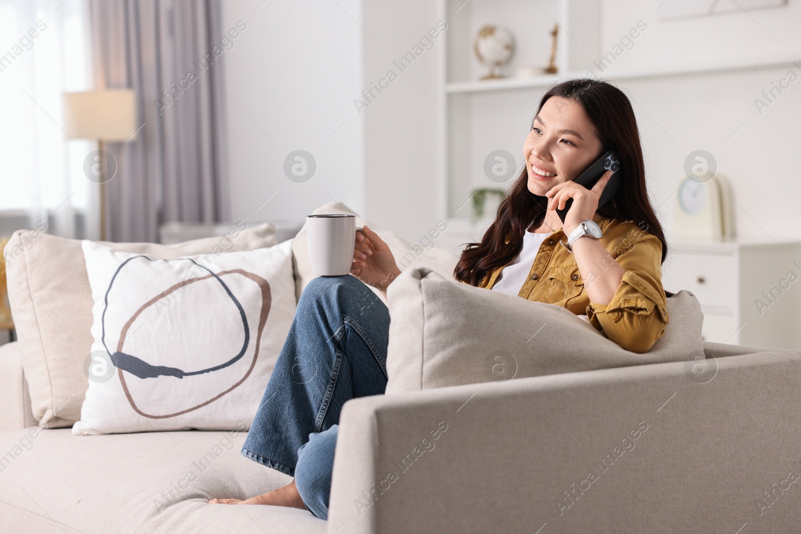 Photo of Smiling woman talking on smartphone at home