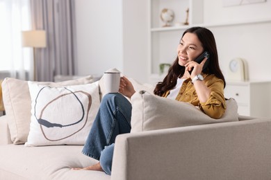 Photo of Smiling woman talking on smartphone at home