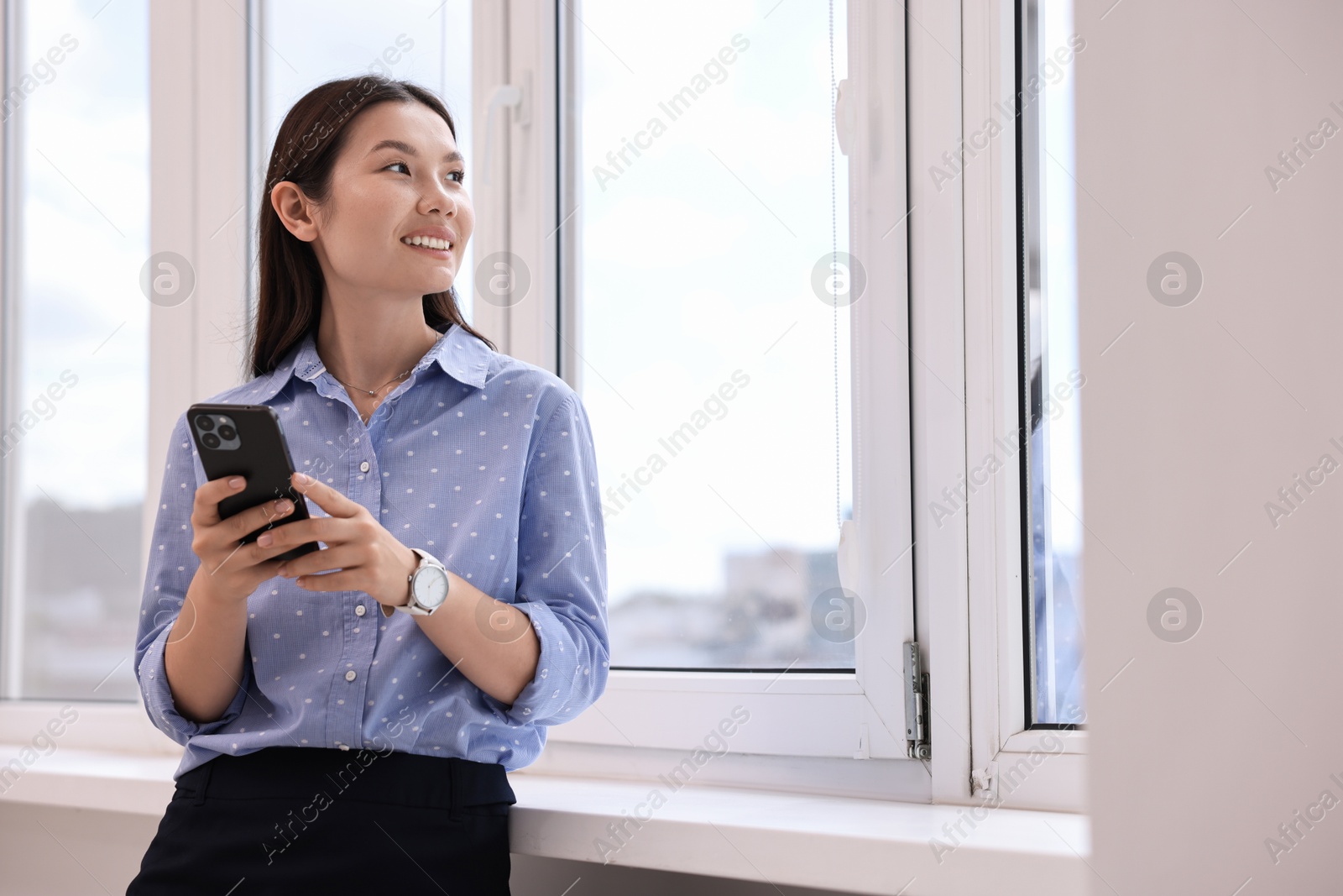 Photo of Smiling businesswoman with smartphone in office. Space for text