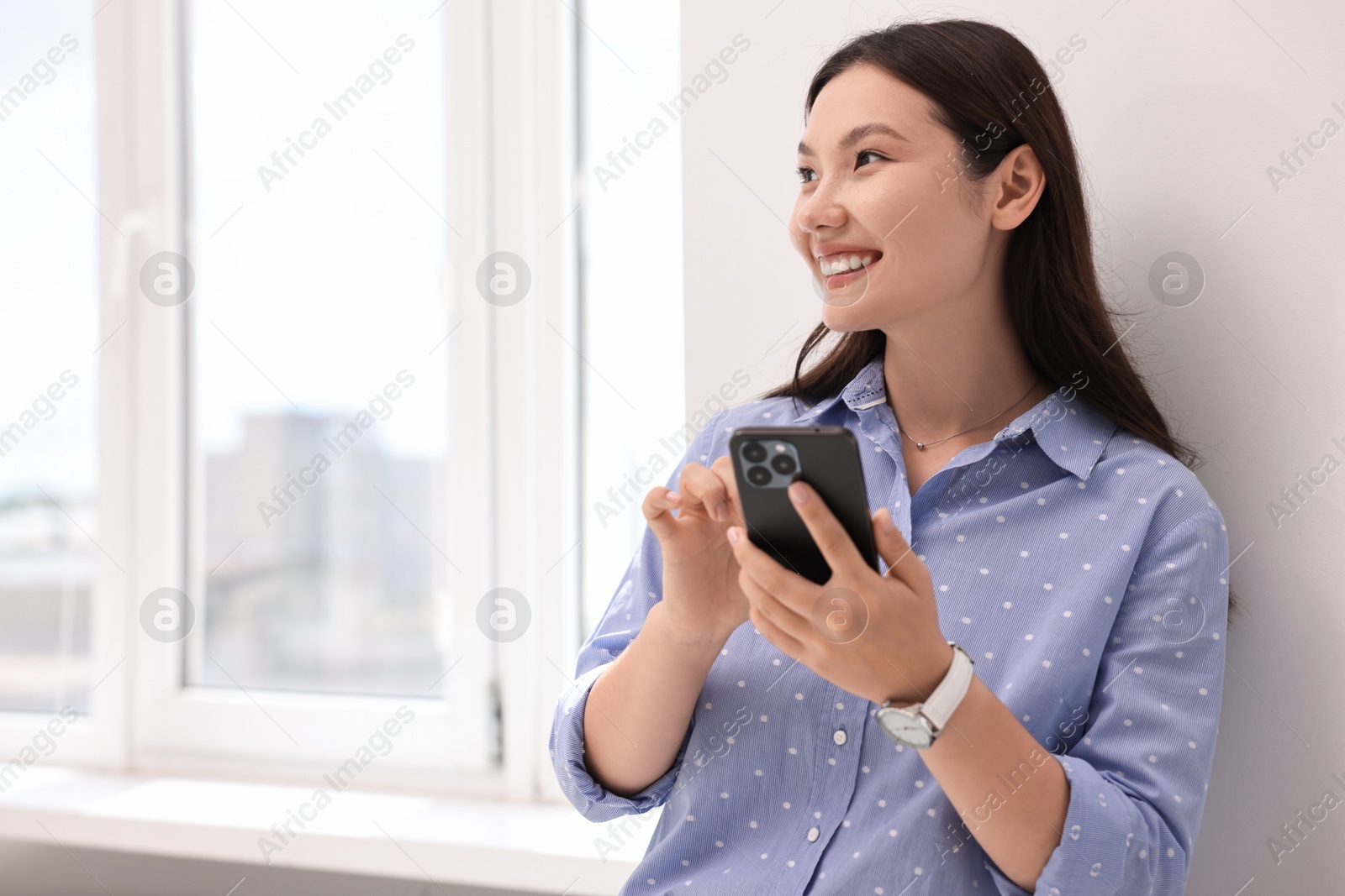 Photo of Smiling businesswoman with smartphone in office. Space for text