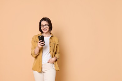 Photo of Smiling woman with smartphone on beige background. Space for text