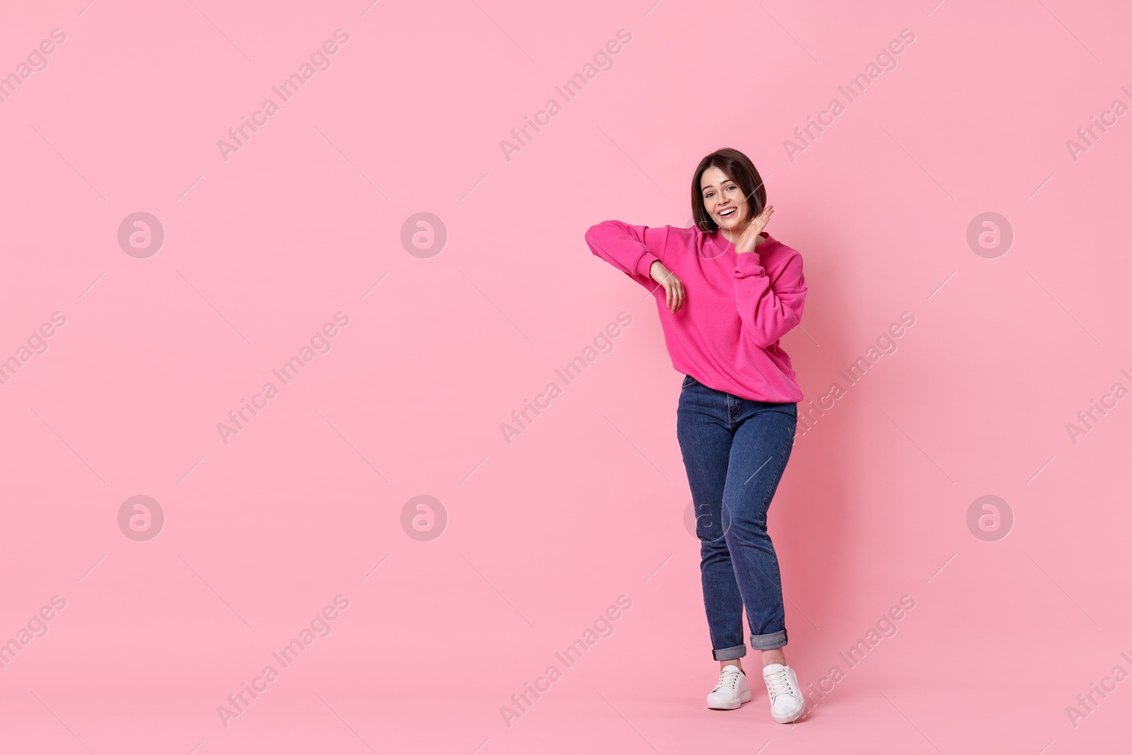 Photo of Smiling woman posing on pink background. Space for text