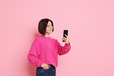 Smiling woman with smartphone on pink background