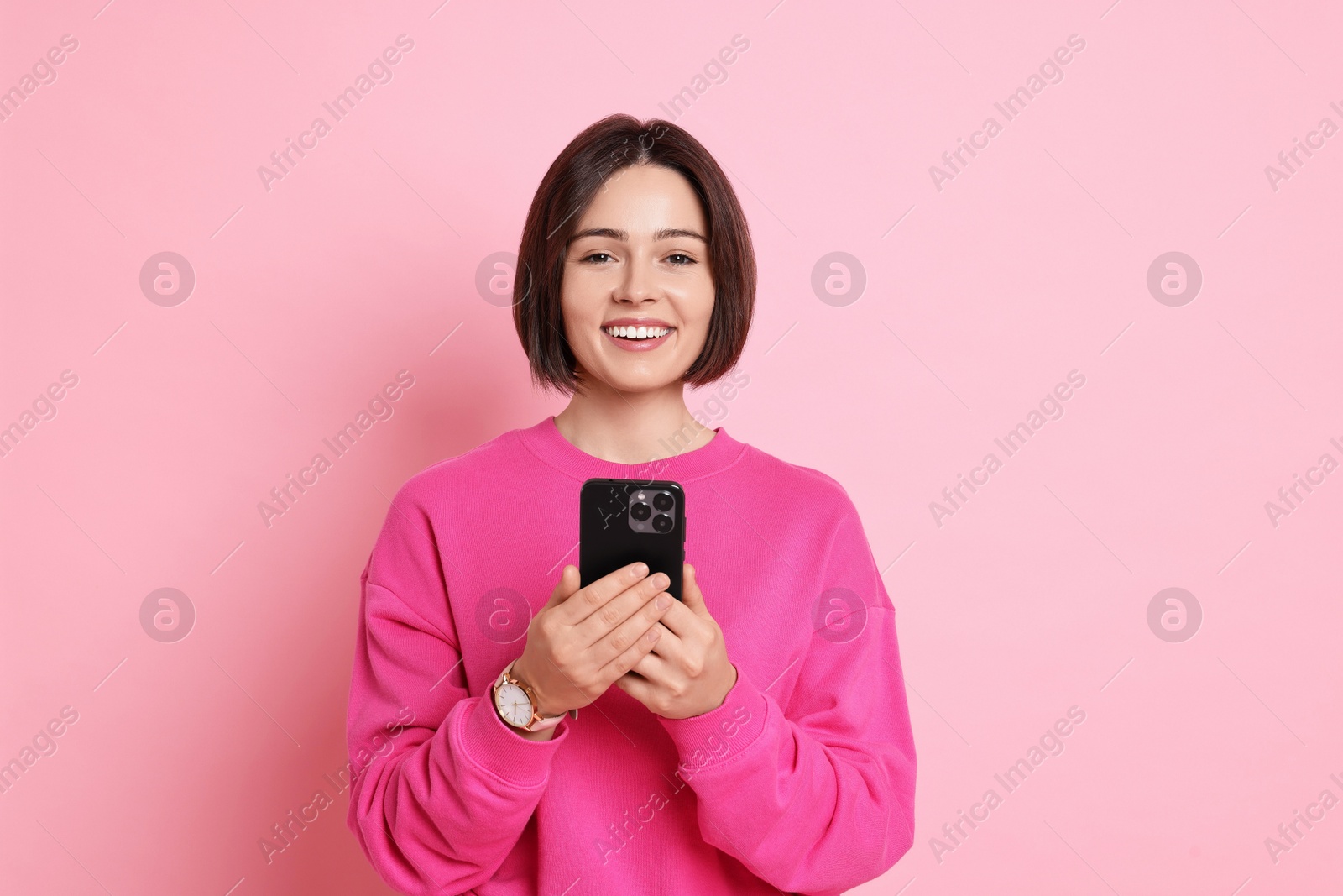 Photo of Smiling woman with smartphone on pink background