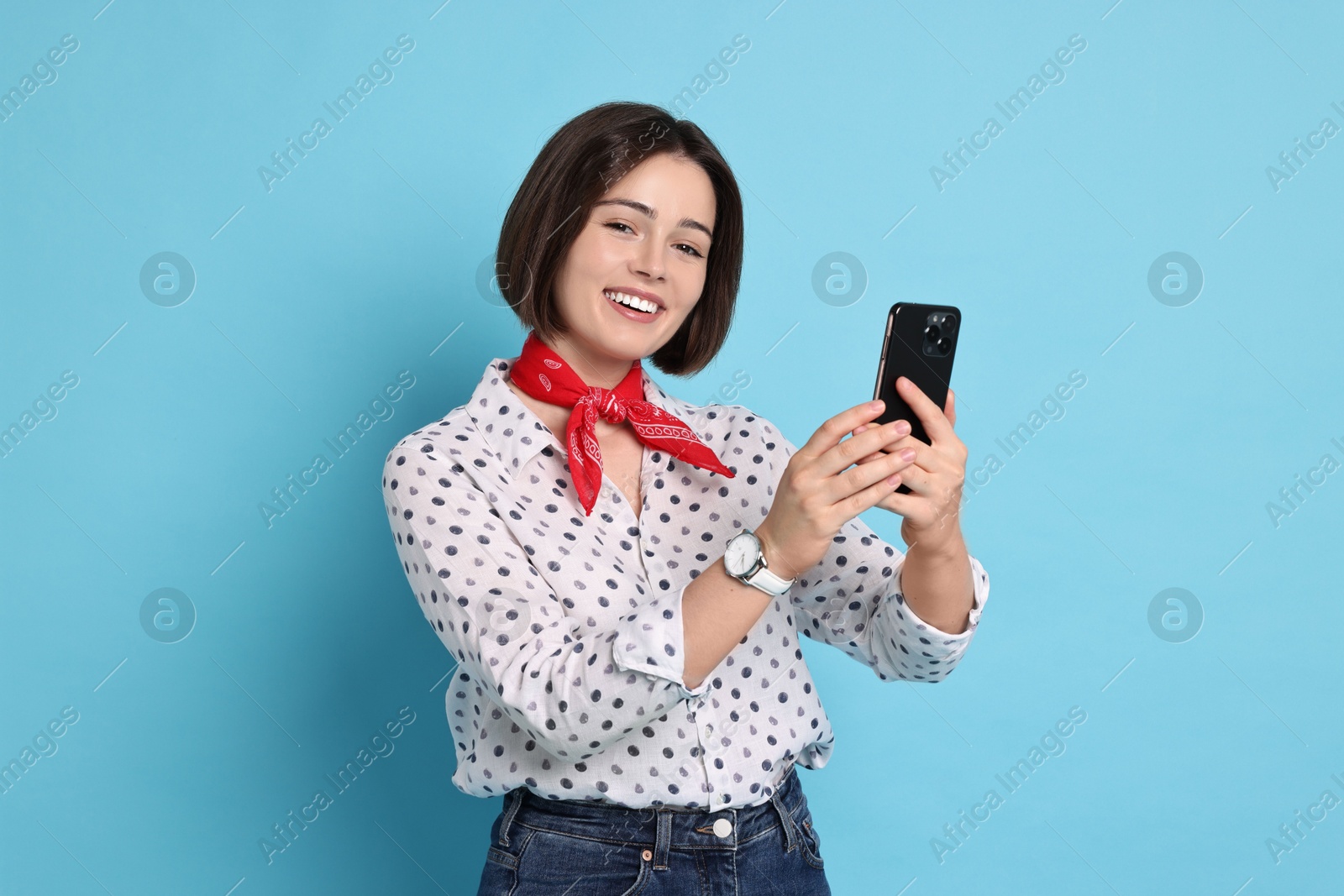 Photo of Smiling woman with smartphone on light blue background