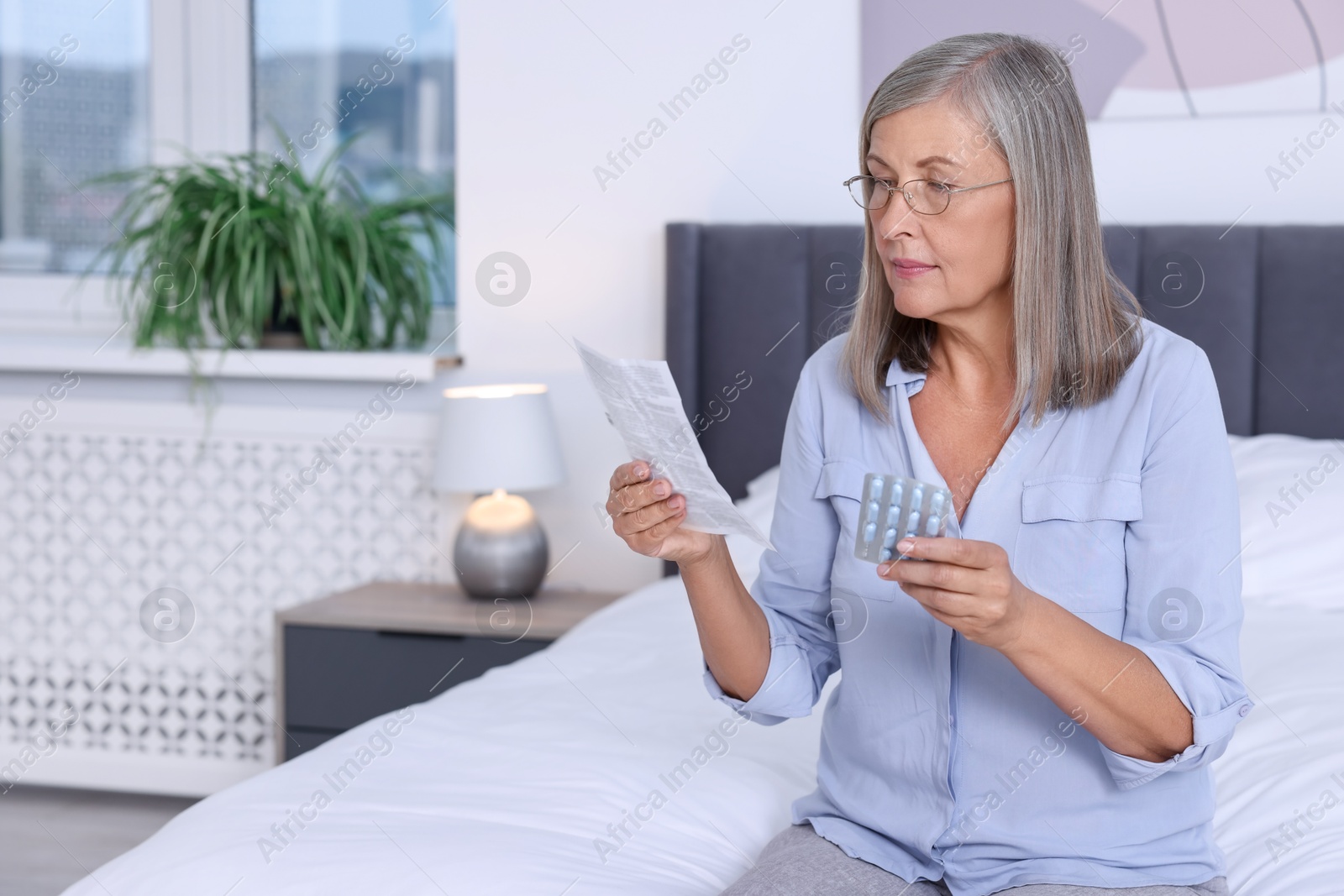 Photo of Senior woman with pills reading medicine instruction at home