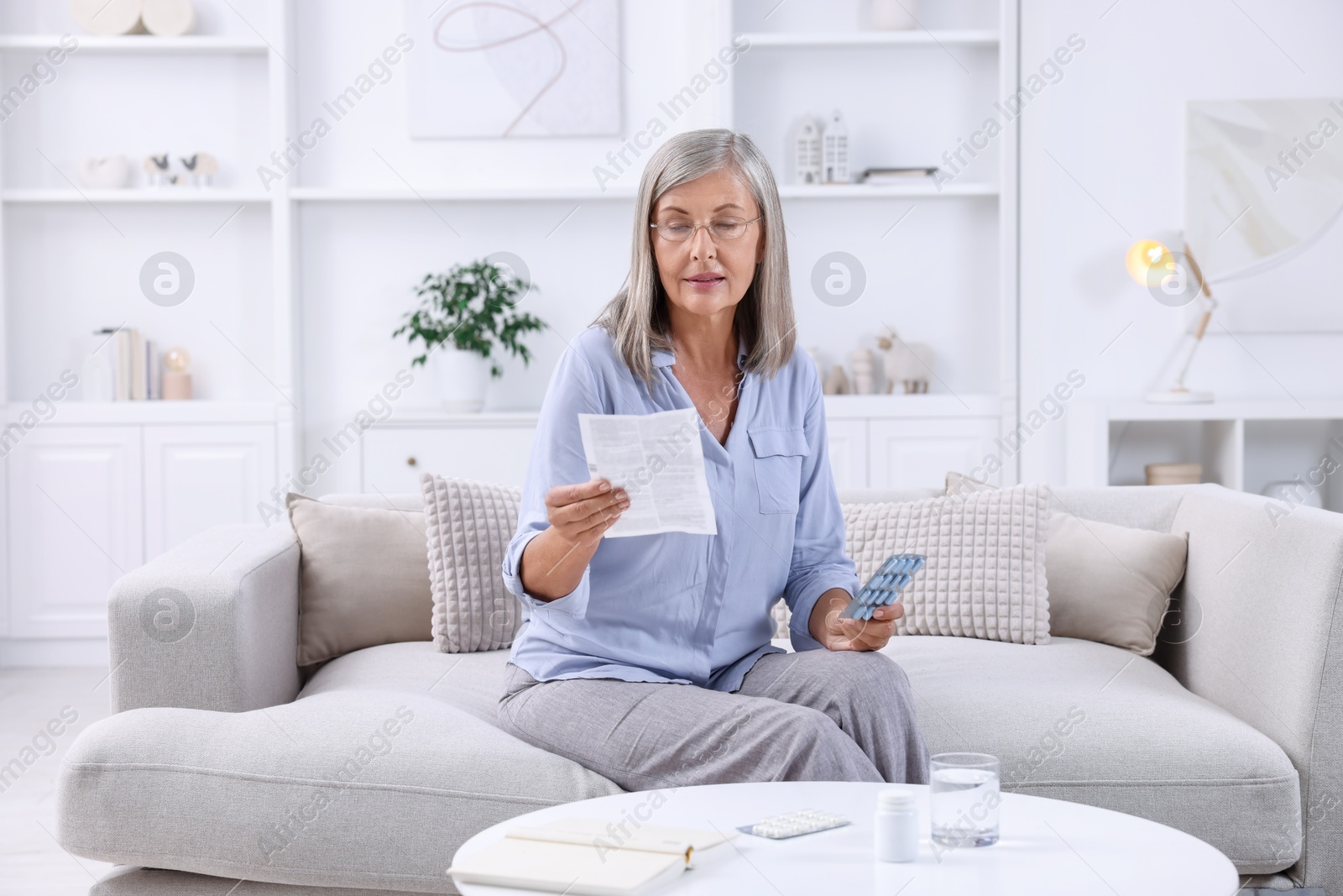 Photo of Senior woman with pills reading medicine instruction at home