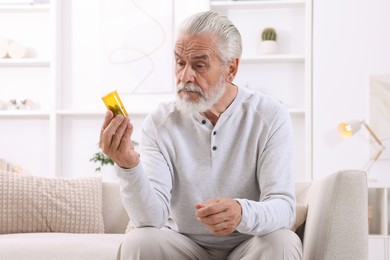 Senior man holding bottle with pills at home